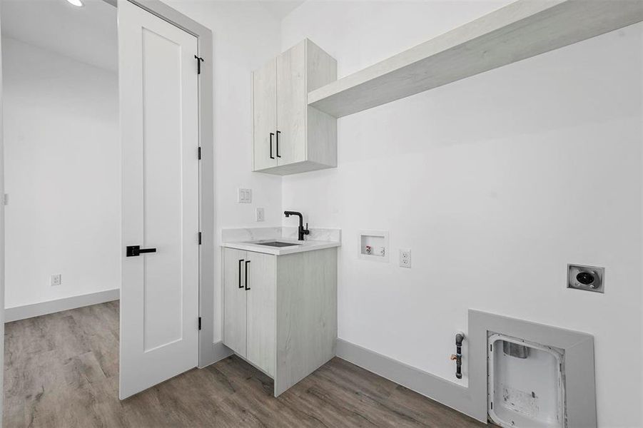 Clothes washing area featuring cabinets, sink, light hardwood / wood-style flooring, and hookup for an electric dryer