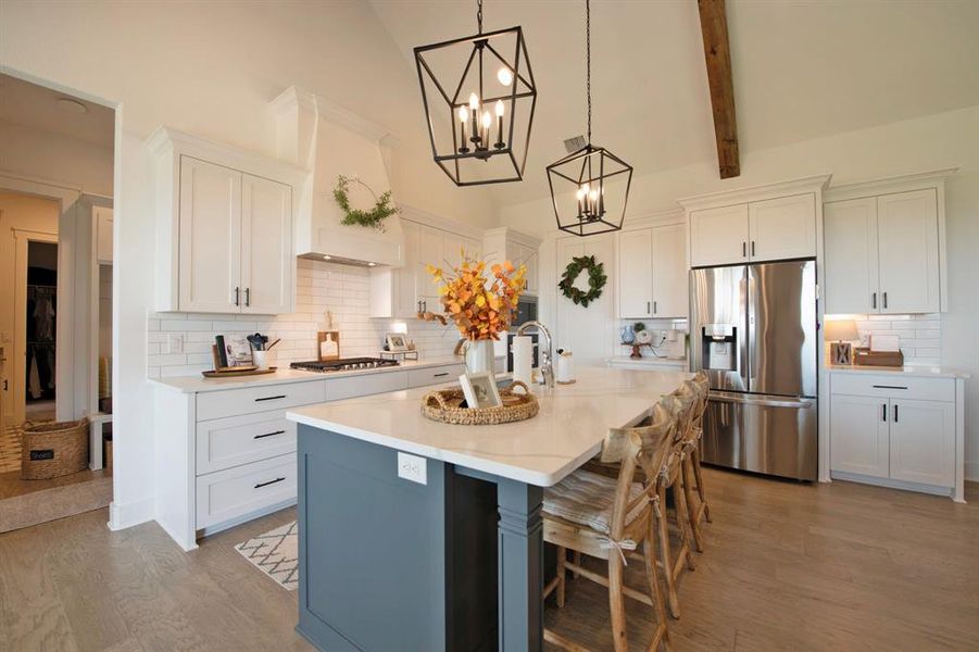 Kitchen with appliances with stainless steel finishes, tasteful backsplash, pendant lighting, a center island with sink, and light wood-style floors