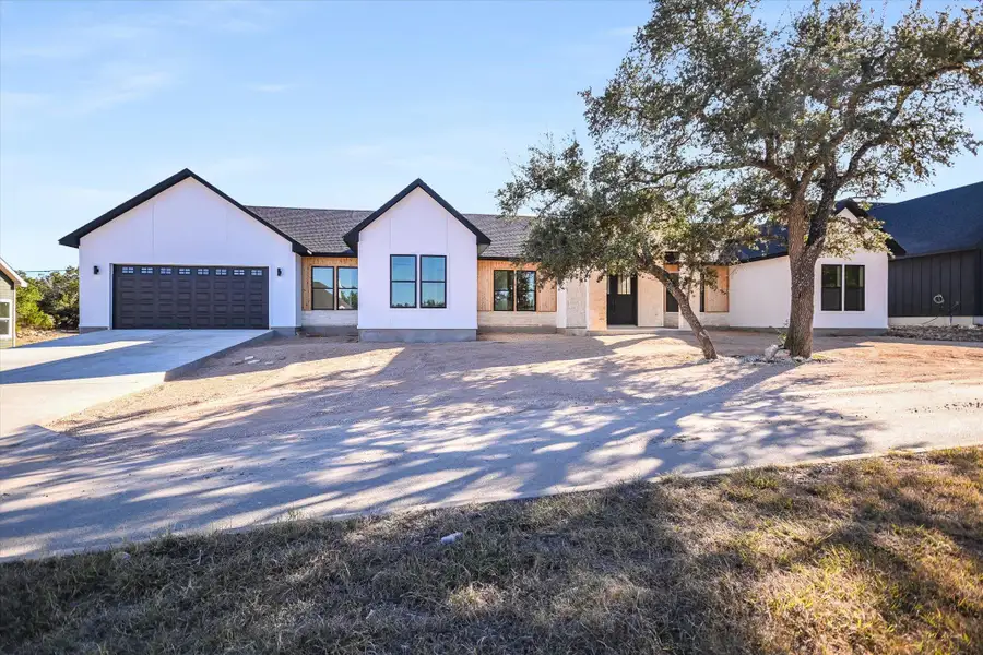 Modern farmhouse style home with driveway, an attached garage, and a shingled roof