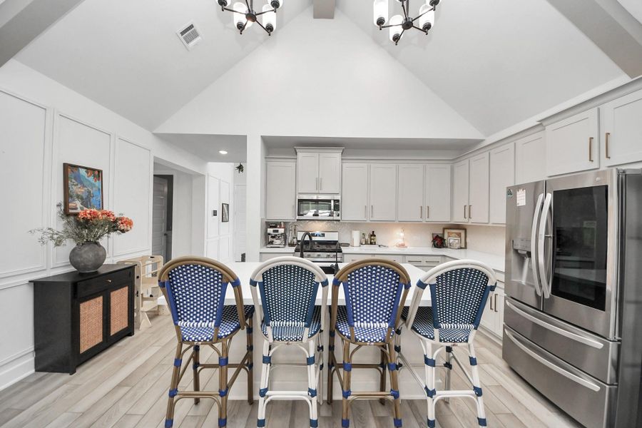 This modern kitchen features high vaulted ceilings, sleek white cabinetry, and stainless steel appliances. An island with stylish seating offers a perfect spot for casual dining, while elegant lighting fixtures add a touch of sophistication. This modern kitchen features high vaulted ceilings, sleek white cabinetry, and stainless steel appliances. An island with stylish seating offers a perfect spot for casual dining, while elegant lighting fixtures add a touch of sophistication.