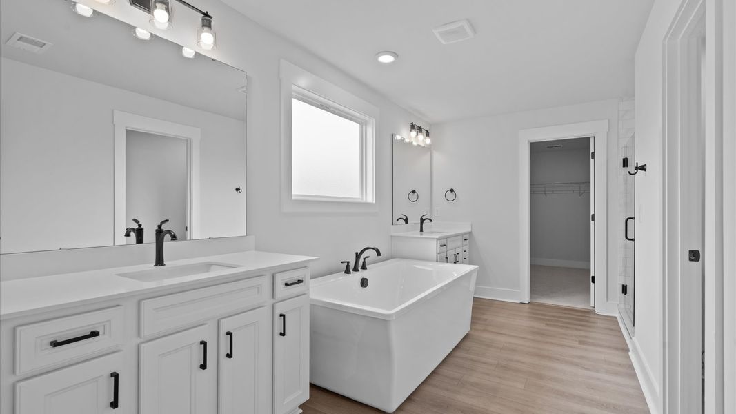 Tasteful primary bath with modern finishes, a walk-in shower, soaking tub, and thoughtful separate vanity layout