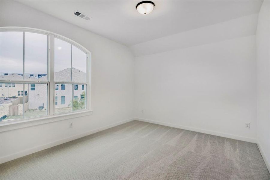 Room featuring a large arched window, light gray carpeting, white painted walls, and a flush-mount ceiling light