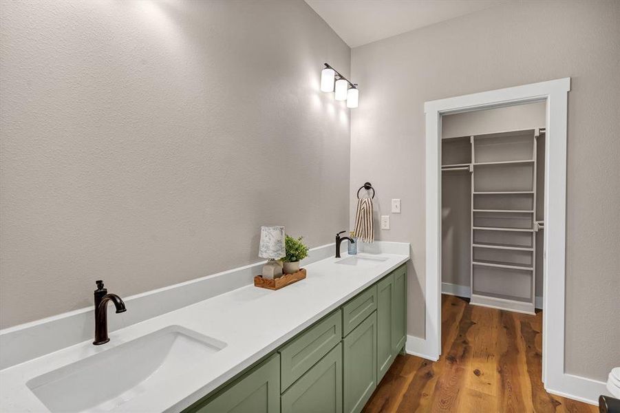 Full bathroom with double vanity, dark wood-style floors, and a walk in closet Full bathroom with double vanity, dark wood-style floors, and a walk in closet
