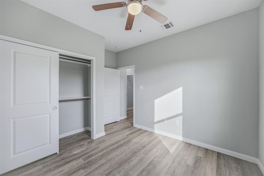 A well-lit bedroom with modern flooring and a practical closet system, ready for personalization.