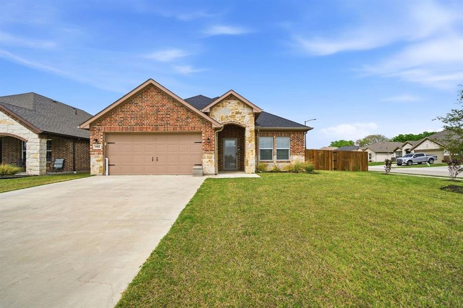 View of front of property with stone siding, an attached garage, driveway, and brick siding