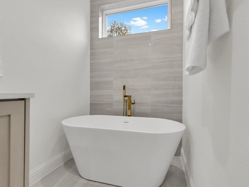 Bathroom featuring tile patterned flooring, vanity, and a bathing tub