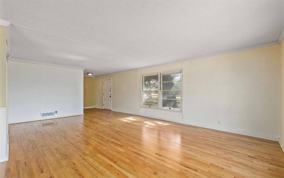 Spare room with crown molding, light wood-style flooring, and a textured ceiling