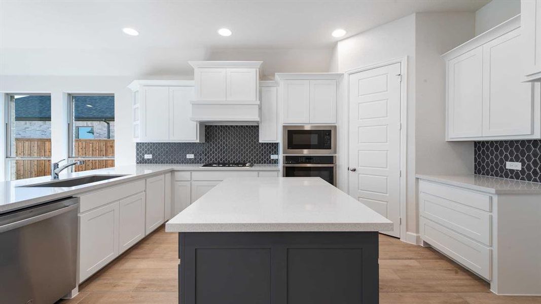 Kitchen with white cabinets, stainless steel appliances, light hardwood / wood-style flooring, and sink