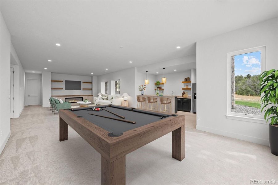 Virtually staged to inspire - the lower level recreation room offers an oversized fireplace, full wet bar, and space for games, movies, and lounging, with walkout access to the covered patio and pergola.