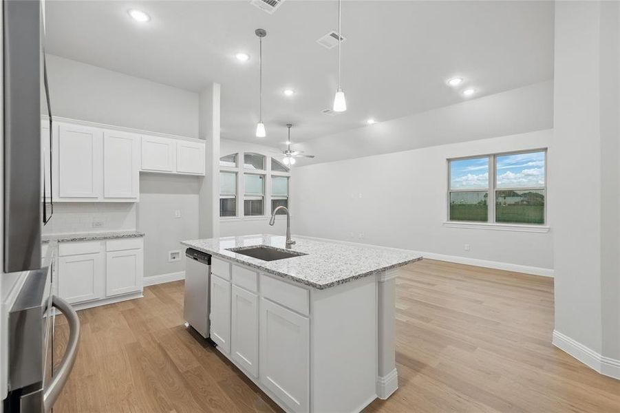 Kitchen with a ceiling fan, white cabinets, light stone counters, light wood-style flooring, and recessed lighting Kitchen with a ceiling fan, white cabinets, light stone counters, light wood-style flooring, and recessed lighting