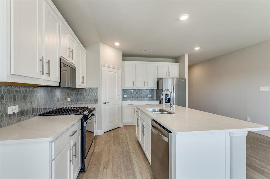 Kitchen with stainless steel appliances, decorative backsplash, light stone countertops, light wood-type flooring, and recessed lighting