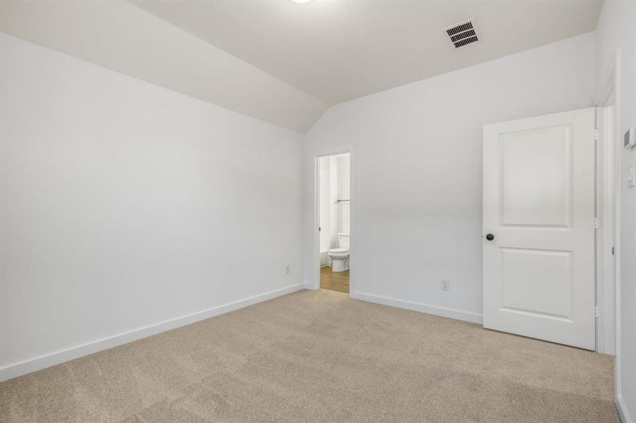 Unfurnished bedroom featuring carpet flooring, lofted ceiling, and ensuite bathroom