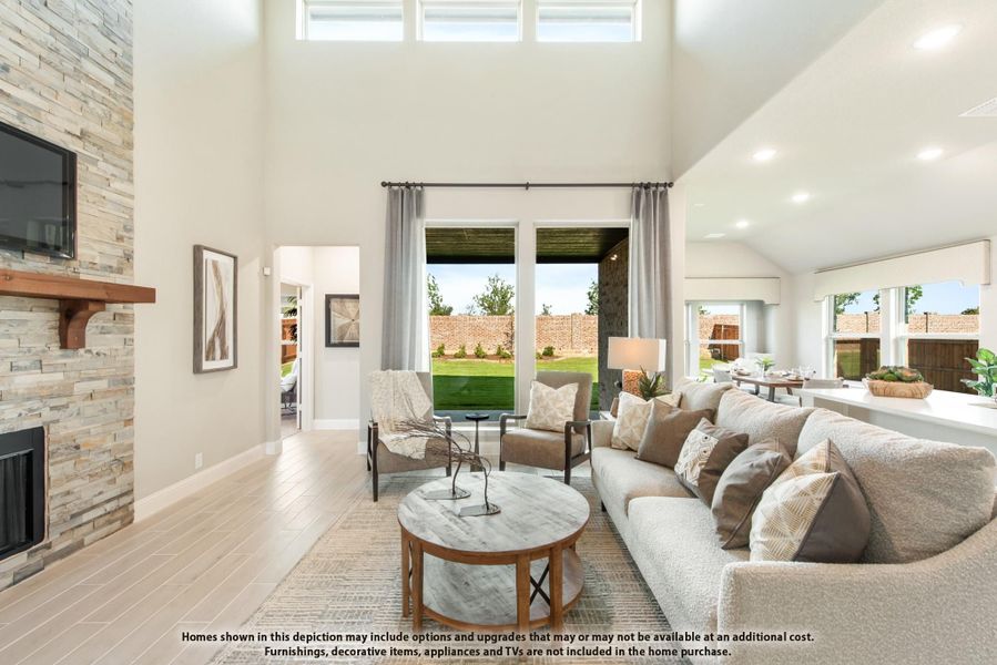Living room with two-story ceiling, stone fireplace, and large windows overlooking backyard patio Living room with two-story ceiling, stone fireplace, and large windows overlooking backyard patio