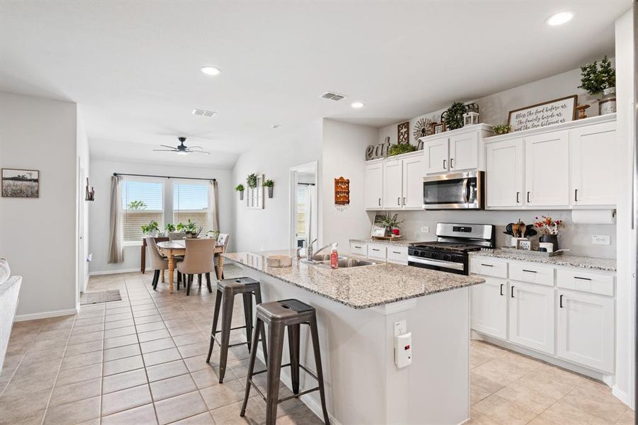 Kitchen with stainless steel appliances, white cabinets, a kitchen breakfast bar, recessed lighting, and light tile patterned floors