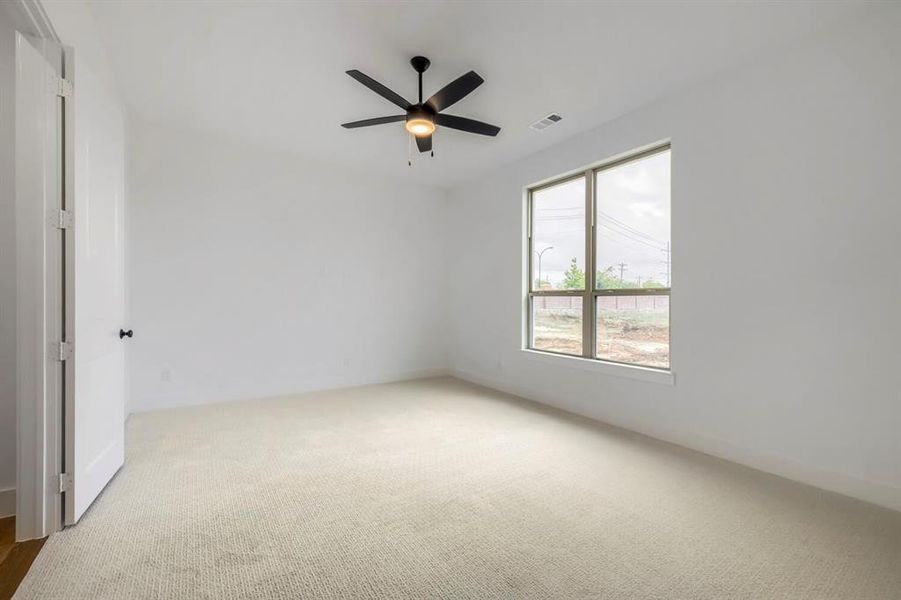 This room features carpet flooring, a ceiling fan with integrated lighting, and a window providing natural light