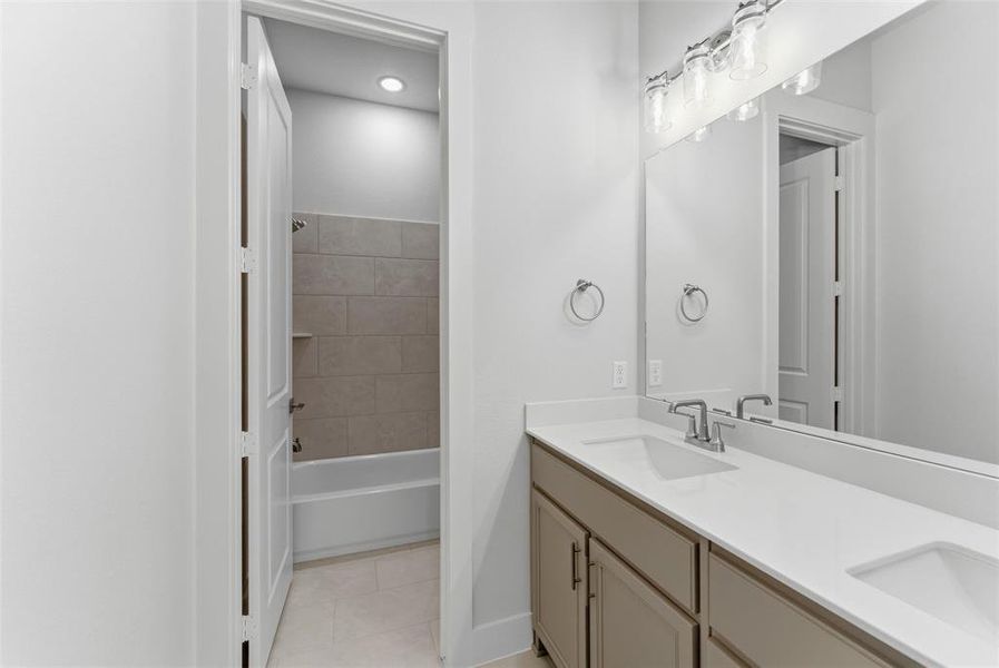 Bathroom with double vanity, light tile patterned flooring, and shower / washtub combination