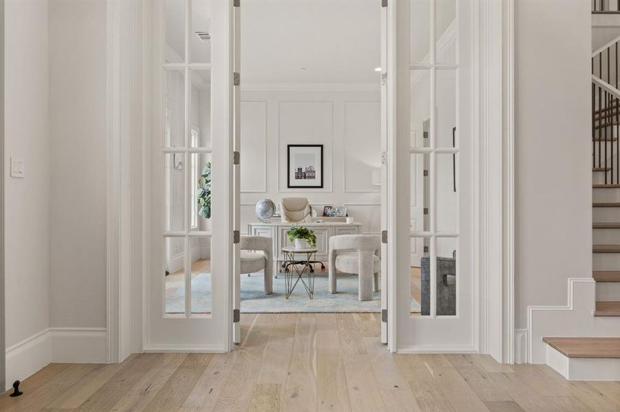 Corridor featuring stairway, hardwood / wood-style flooring, crown molding, a decorative wall, and french doors Corridor featuring stairway, hardwood / wood-style flooring, crown molding, a decorative wall, and french doors