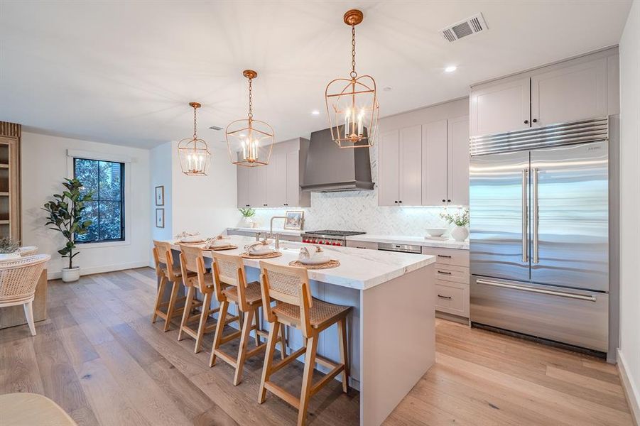 Kitchen featuring backsplash, stainless steel built in fridge, pendant lighting, light wood finished floors, and recessed lighting Kitchen featuring backsplash, stainless steel built in fridge, pendant lighting, light wood finished floors, and recessed lighting