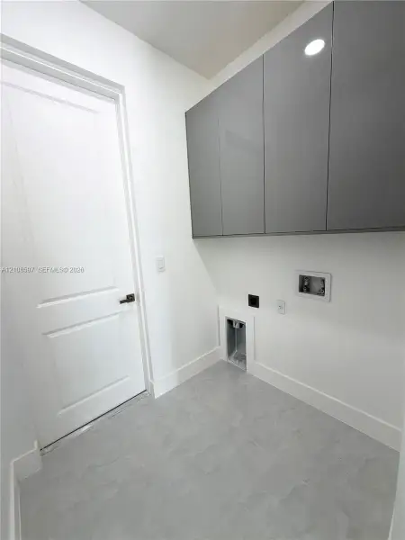 Grey high-gloss wall-mounted cabinetry, large-format tiled flooring, and a solid-core paneled door with matte black hardware
