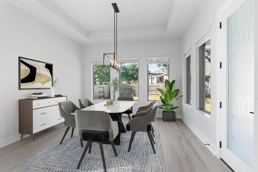 Dining area with light wood-type flooring, a tray ceiling, and a chandelier