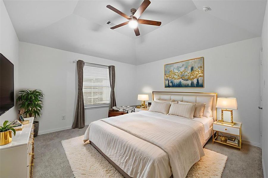 Bedroom with light colored carpet, a ceiling fan, and a raised ceiling Bedroom with light colored carpet, a ceiling fan, and a raised ceiling