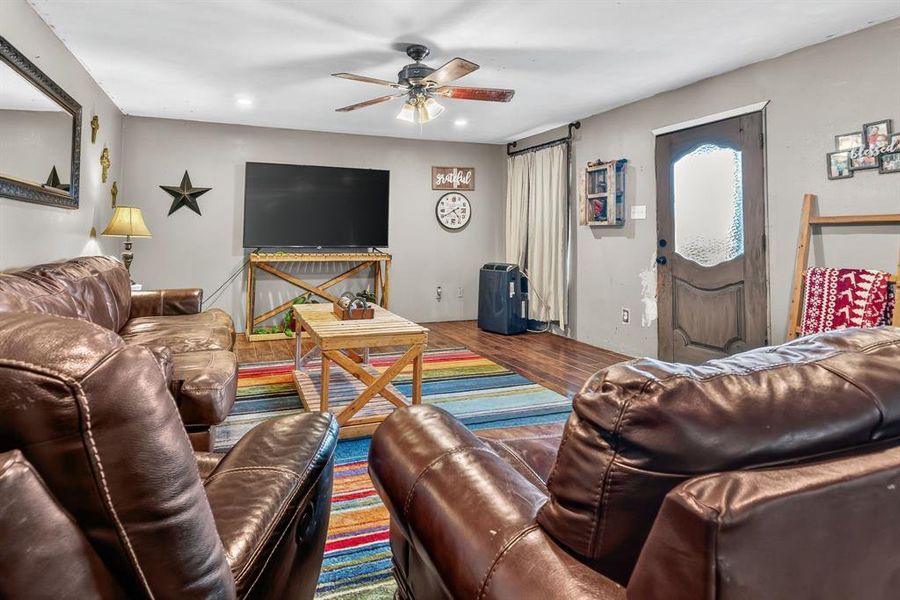 Living room featuring wood finished floors, a ceiling fan, and a barn door Living room featuring wood finished floors, a ceiling fan, and a barn door