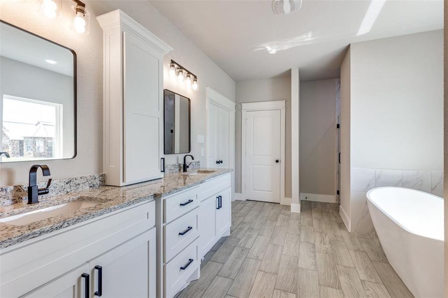 Bathroom featuring vanity, a bath, and hardwood / wood-style flooring