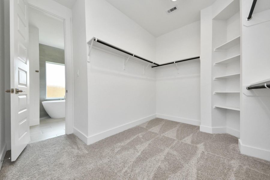 Walk-in closet that epitomizes luxury and practicality. This generously sized space features built-in shelving, offering abundant room for impeccable organization. High ceilings and recessed lighting create a bright and welcoming ambiance.