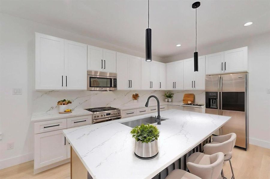 Kitchen featuring light wood-style floors, appliances with stainless steel finishes, decorative backsplash, white cabinetry, and recessed lighting Kitchen featuring light wood-style floors, appliances with stainless steel finishes, decorative backsplash, white cabinetry, and recessed lighting