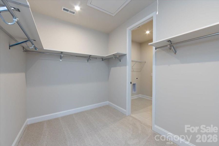 Primary walk-in closet with door access to the laundry room