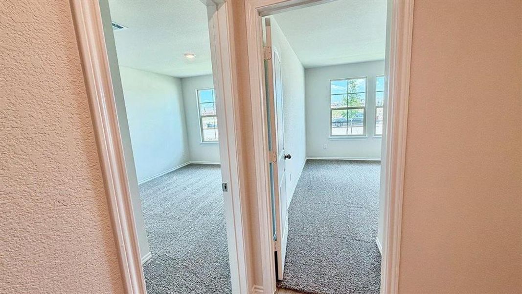 Two separate rooms featuring light neutral wall paint, gray textured carpeting, white baseboards, and white window frames