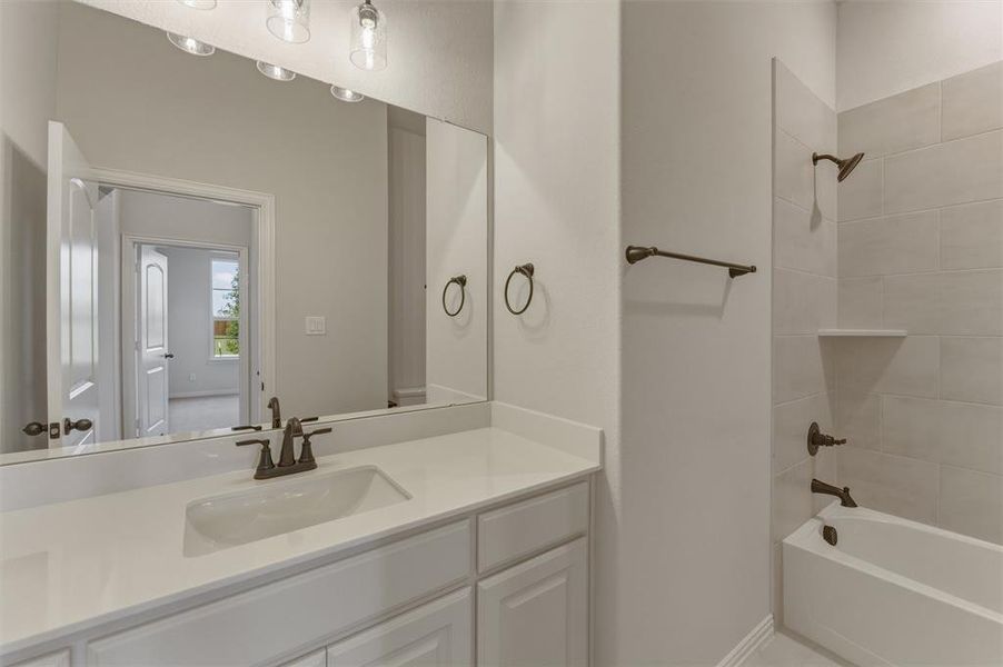 Bathroom featuring a white vanity with an integrated sink, bronze-finish faucet, and a large wall-mounted mirror Bathroom featuring a white vanity with an integrated sink, bronze-finish faucet, and a large wall-mounted mirror
