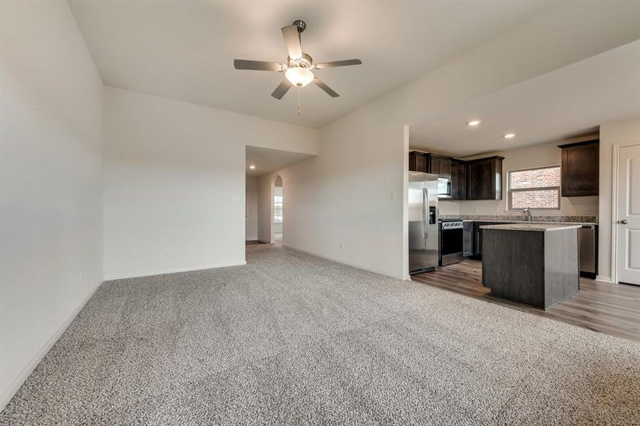 Kitchen with stainless steel appliances, ceiling fan, a center island, dark brown cabinets, and light colored carpet