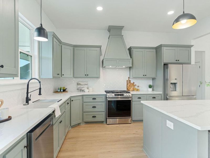 Kitchen with hanging light fixtures, stainless steel appliances, light wood-style flooring, light stone countertops, and backsplash