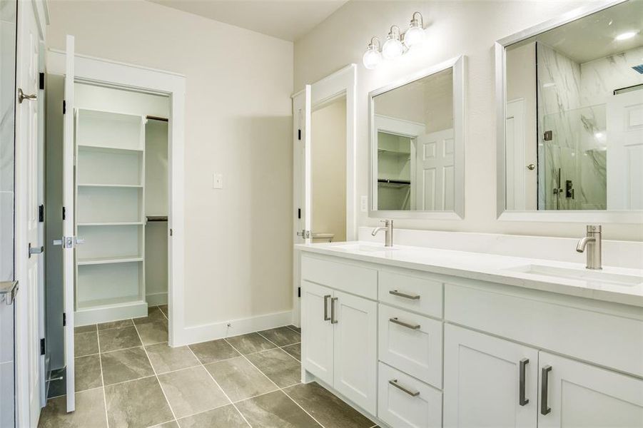 Full bathroom featuring a spacious closet, a marble finish shower, and a sink