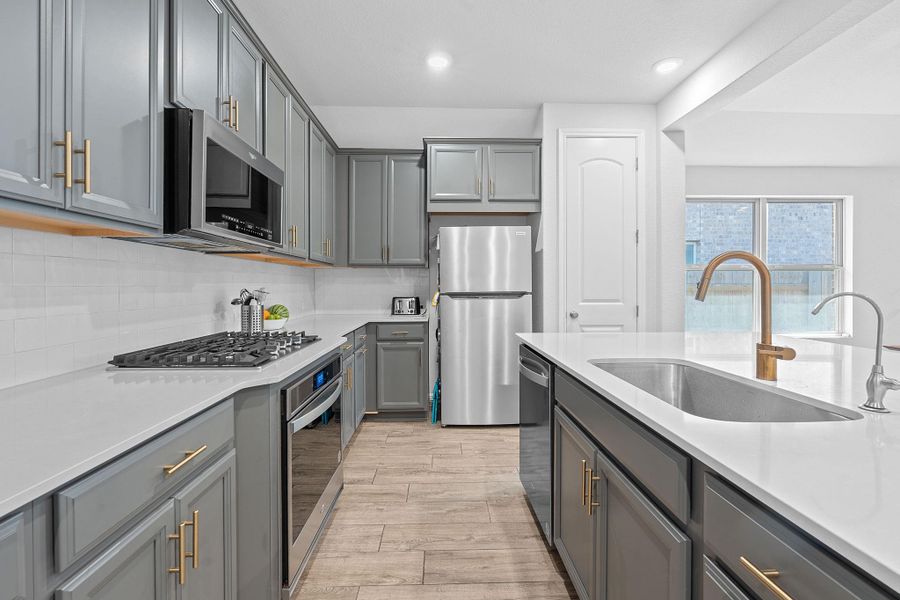 Kitchen featuring gray cabinets, tasteful backsplash, appliances with stainless steel finishes, light wood-style floors, and recessed lighting Kitchen featuring gray cabinets, tasteful backsplash, appliances with stainless steel finishes, light wood-style floors, and recessed lighting