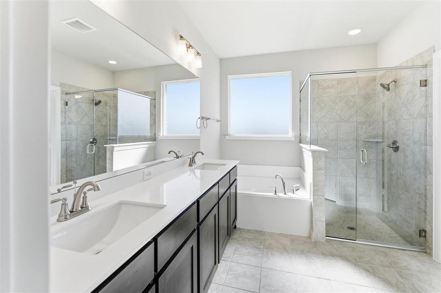 Full bathroom featuring double vanity, a garden tub, and a stall shower