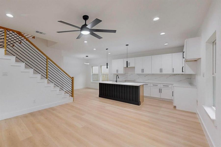 Kitchen featuring an island with sink, light wood-type flooring, decorative backsplash, light countertops, and recessed lighting Kitchen featuring an island with sink, light wood-type flooring, decorative backsplash, light countertops, and recessed lighting