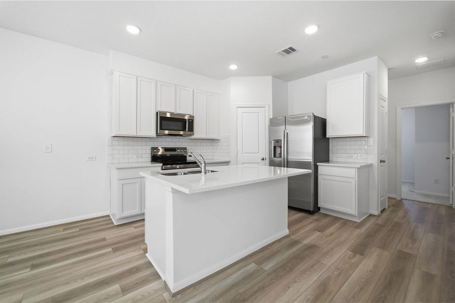 Kitchen featuring stainless steel appliances, a kitchen island with sink, white cabinets, light wood finished floors, and recessed lighting Kitchen featuring stainless steel appliances, a kitchen island with sink, white cabinets, light wood finished floors, and recessed lighting