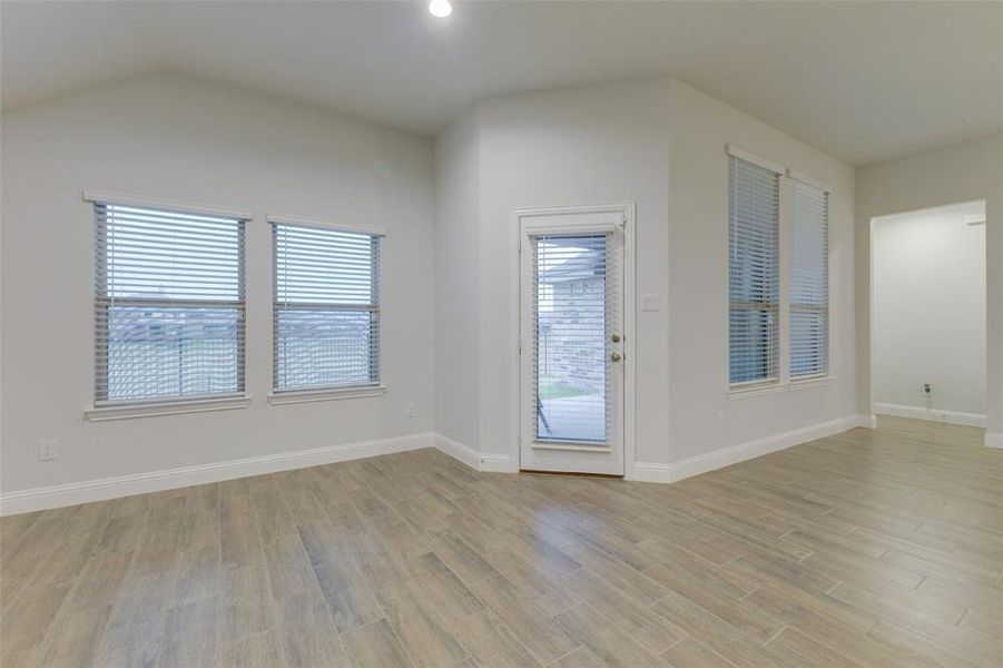 Unfurnished room featuring light wood-type flooring and vaulted ceiling