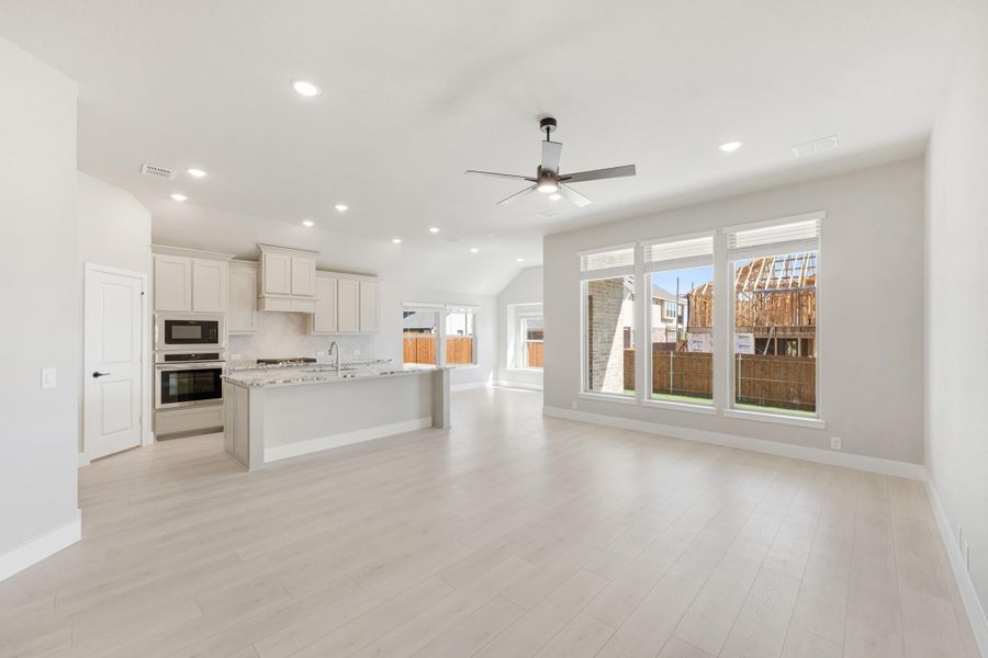Open-concept living area and kitchen with center island, light wood floors, and ceiling fan