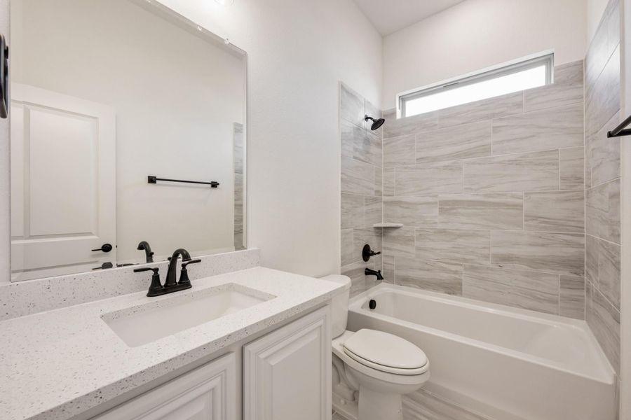 Bathroom with white quartz vanity, tub-shower combo with gray tile surround, and black fixtures Bathroom with white quartz vanity, tub-shower combo with gray tile surround, and black fixtures