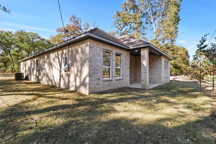 View of property exterior with a patio area, a yard, and central AC