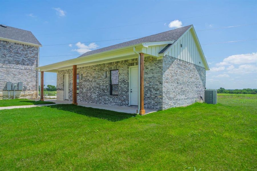 View of home's exterior with board and batten siding, a yard, brick siding, and roof with shingles View of home's exterior with board and batten siding, a yard, brick siding, and roof with shingles