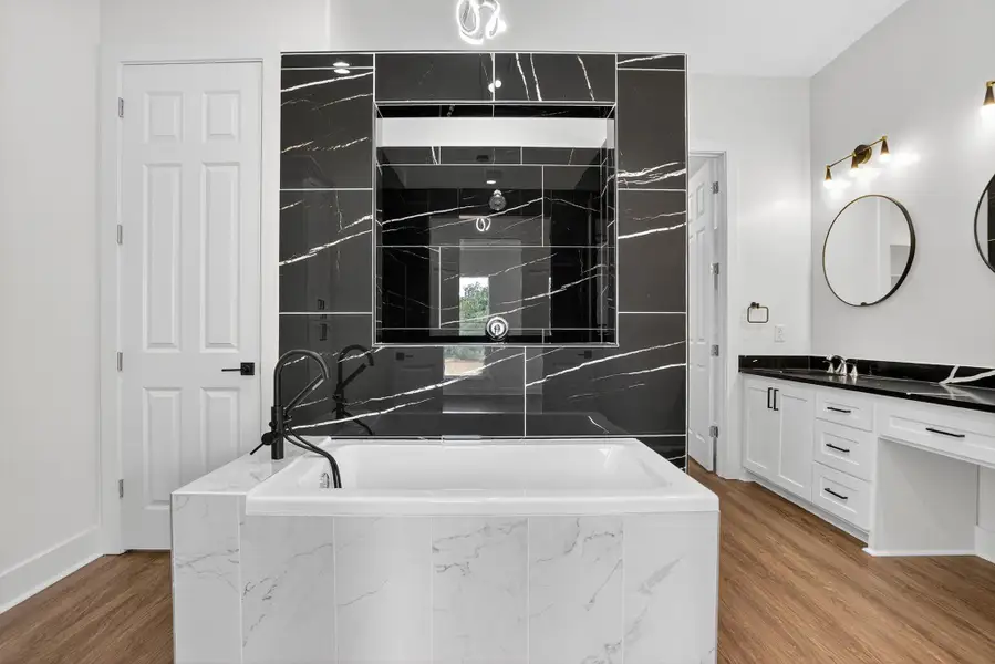 Full bath featuring vanity, a garden tub, and light wood-style flooring Full bath featuring vanity, a garden tub, and light wood-style flooring