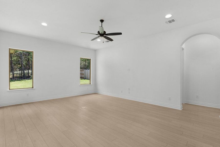 A spacious room offers ample natural light and a modern ceiling fan for comfort.