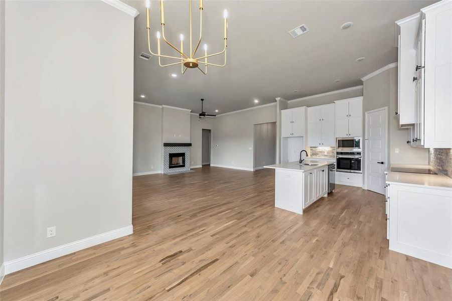 Kitchen featuring light wood-type flooring, white cabinets, a kitchen island with sink, stainless steel appliances, and decorative backsplash