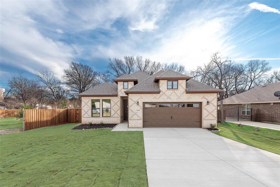 View of front of property with a shingled roof, brick siding, driveway, and an attached garage