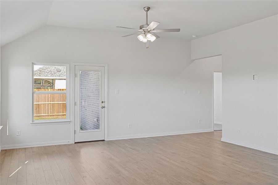 Unfurnished living room with light wood-type flooring, vaulted ceiling, and ceiling fan