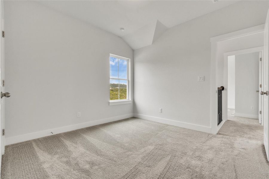 A well-lit bedroom with high ceilings and a broad window showcasing an appealing outdoor view.